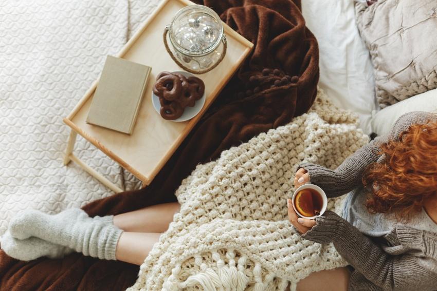 Frau mit Kuscheldecke und warmen Socken